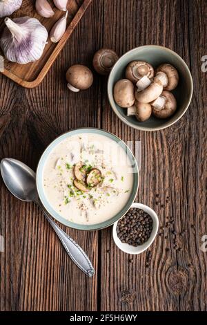 Délicieux déjeuner, soupe de crème de champignons apaisante avec ciboulette fraîchement hachée sur fond de bois rustique Banque D'Images