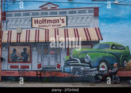 Williamsburg, Ohio, États-Unis. 26 mars 2021. DAVE WHITSON fait une pause à l'extérieur de la boutique Holtman's Donut à Williamsburg, Ohio, alors qu'il poursuit sa promenade d'un océan à l'autre vendredi matin le 26 mars 2021. Holtman's est ouvert, et a déplacé toutes les places de client à l'extérieur.Whitson, un professeur d'école secondaire de Portland, OU a été inspiré de marcher d'un océan à l'autre après avoir fait une marche de Cincinnati à Denver en 2019.en février 2020, Whitson a commencé à marcher à Cape Henloopen, DE et a suspendu sa marche deux fois en 2020 en raison de restrictions et de préoccupations concernant COVID-19.après avoir atteint Cincinnati le 27 mars, Whitson retournera à h Banque D'Images