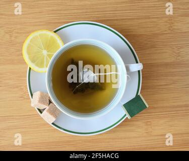 Tasse de thé vert avec des tranches de citron et des morceaux de sucre vue sur la table. Banque D'Images
