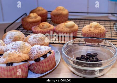 Cupcakes à l'avant avec des chips de crème et de chocolat, avec d'autres dans l'arrière-plan sur une grille de refroidissement Banque D'Images