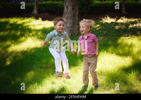 Deux frères garçons jouant et sautant à l'extérieur dans un parc. Banque D'Images
