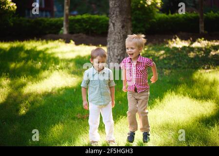 Deux frères garçons jouant et sautant à l'extérieur dans un parc. Banque D'Images