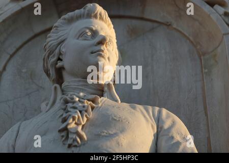 Statue en pierre de génie musical, compositeur Wolfgang Amadeus Mozart, monument de 1898, vue rapprochée horizontale à angle bas, lumière chaude de l'après-midi Banque D'Images