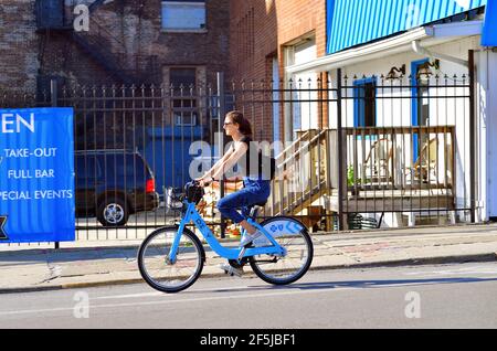 Chicago, Illinois, États-Unis. Femme utilisant un vélo loué ou un vélo partagé dans une voie de vélo de rue désignée sur le côté nord de la ville. Banque D'Images