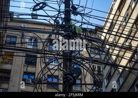 Bucarest, Roumanie - 11 mars 2021 : de nombreux câbles d'électricité, d'Internet et de communication sont suspendus sur un pilier de Bucarest. Banque D'Images