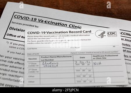 Bethesda, MD, Etats-Unis 03-22-2021: Une carte de vaccination COVID 19 sur un bureau en bois. La carte détaille la date, le type et le numéro de dose de l'administrateur Banque D'Images