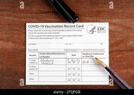Bethesda, MD, Etats-Unis 03-22-2021: Une carte de vaccination COVID 19 sur un bureau en bois. La carte détaille la date, le type et le numéro de dose de l'administrateur Banque D'Images