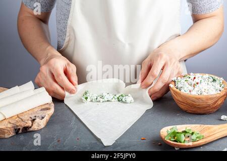 Une femme caucasienne remplit des feuilles de pâte phyllo connues sous le nom Yufka avec farce au fromage pour faire le traditionnel turc sigara boregi (cigarette borek) une dors Banque D'Images