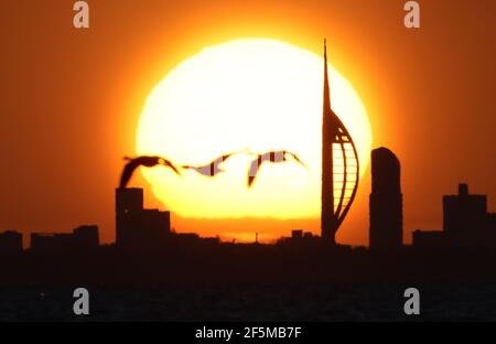 Portsmouth, Hampshire. 27 mars 2021. Météo Royaume-Uni. Lever de soleil sur la Tour Spinnaker et Portsmouth, vue de l'autre côté du Solent, lors d'une matinée ensoleillée et lumineuse avec des douches occasionnelles. Credit Stuart Martin/Alay Live News Banque D'Images