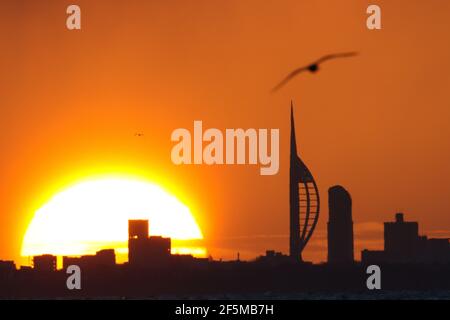 Portsmouth, Hampshire. 27 mars 2021. Météo Royaume-Uni. Lever de soleil sur la Tour Spinnaker et Portsmouth, vue de l'autre côté du Solent, lors d'une matinée ensoleillée et lumineuse avec des douches occasionnelles. Credit Stuart Martin/Alay Live News Banque D'Images