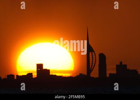 Portsmouth, Hampshire. 27 mars 2021. Météo Royaume-Uni. Lever de soleil sur la Tour Spinnaker et Portsmouth, vue de l'autre côté du Solent, lors d'une matinée ensoleillée et lumineuse avec des douches occasionnelles. Credit Stuart Martin/Alay Live News Banque D'Images