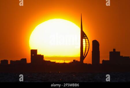 Portsmouth, Hampshire. 27 mars 2021. Météo Royaume-Uni. Lever de soleil sur la Tour Spinnaker et Portsmouth, vue de l'autre côté du Solent, lors d'une matinée ensoleillée et lumineuse avec des douches occasionnelles. Credit Stuart Martin/Alay Live News Banque D'Images