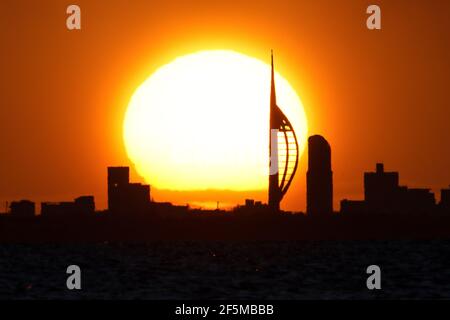 Portsmouth, Hampshire. 27 mars 2021. Météo Royaume-Uni. Lever de soleil sur la Tour Spinnaker et Portsmouth, vue de l'autre côté du Solent, lors d'une matinée ensoleillée et lumineuse avec des douches occasionnelles. Credit Stuart Martin/Alay Live News Banque D'Images