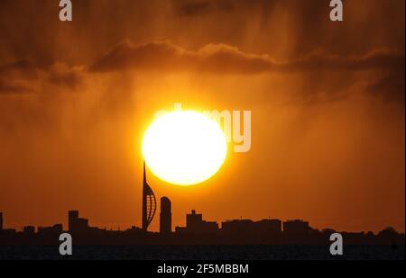 Portsmouth, Hampshire. 27 mars 2021. Météo Royaume-Uni. Lever de soleil sur la Tour Spinnaker et Portsmouth, vue de l'autre côté du Solent, lors d'une matinée ensoleillée et lumineuse avec des douches occasionnelles. Credit Stuart Martin/Alay Live News Banque D'Images