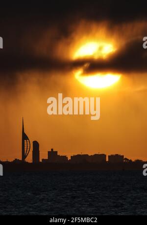 Portsmouth, Hampshire. 27 mars 2021. Météo Royaume-Uni. Lever de soleil sur la Tour Spinnaker et Portsmouth, vue de l'autre côté du Solent, lors d'une matinée ensoleillée et lumineuse avec des douches occasionnelles. Credit Stuart Martin/Alay Live News Banque D'Images