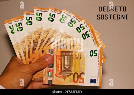 Tenir à la main des billets avec le signe 'Defreto Sostegni' traduit dans l'aide financière. Incitation du gouvernement italien. Banque D'Images