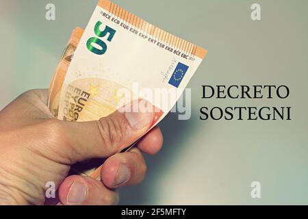Tenir à la main des billets avec le signe 'Defreto Sostegni' traduit dans l'aide financière. Incitation du gouvernement italien. Banque D'Images
