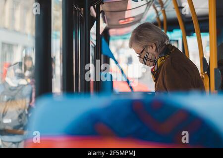 Shepherd's Bush, Londres | Royaume-Uni - 2021.03.22 : une femme âgée sous masque médical quitte le bus pendant une pandémie du coronavirus Banque D'Images