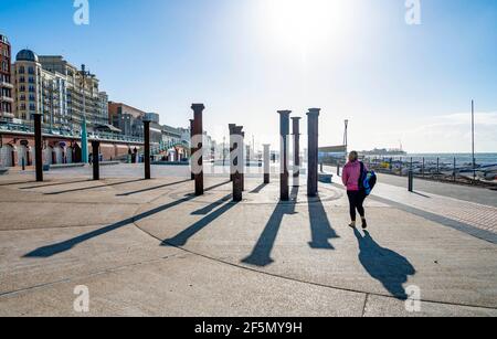 Brighton Royaume-Uni 27 mars 2021 - les marcheurs profitent d'une matinée ensoleillée et froide à côté de l'installation d'art Golden Spiral sur le front de mer de Brighton . Le temps devrait devenir beaucoup plus chaud la semaine prochaine avec des températures qui devraient atteindre plus de 20 degrés dans certaines parties du Royaume-Uni : crédit Simon Dack / Alamy Live News Banque D'Images