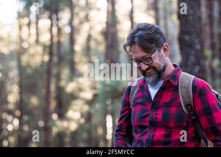 Homme en randonnée et en appréciant dans une forêt de bois. Vue latérale d'un homme portant un sac marchant dans une forêt. Heureux adulte jeune caucasien mâle portra Banque D'Images