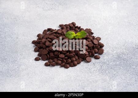 Gouttes de chocolat sur fond de béton gris morceaux de chocolat pour la décoration de dessert. Banque D'Images