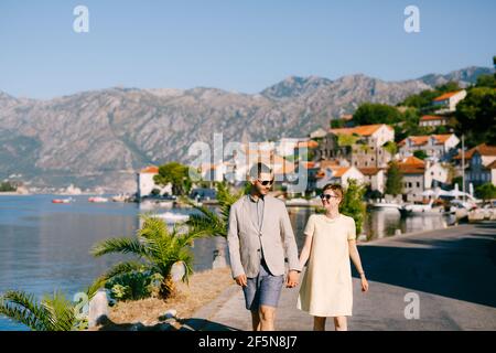 Un couple aimant marche en tenant les mains le long du remblai de La vieille ville de Perast Banque D'Images