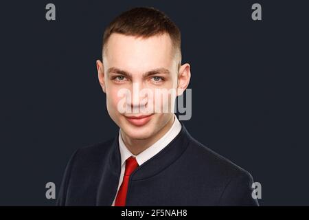 Jeune homme d'affaires charmant portant une suite se dresse sur un fond sombre. Prise de vue en studio. Banque D'Images