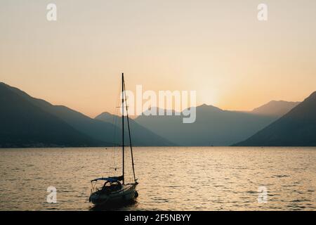 Silhouette d'un yacht amarré sur fond de soleil couchant sur les montagnes. Coucher de soleil jaune vif sur les montagnes de la baie Banque D'Images