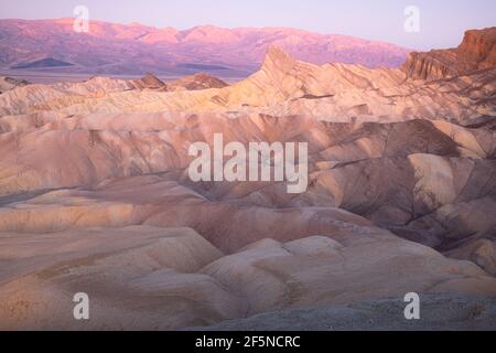 Vue au coucher du soleil ou au lever du soleil sur Zabriskie point et le terrain rocheux sédimentaire accidenté du paysage des badlands dans le parc national de Death Valley Park, États-Unis. Banque D'Images