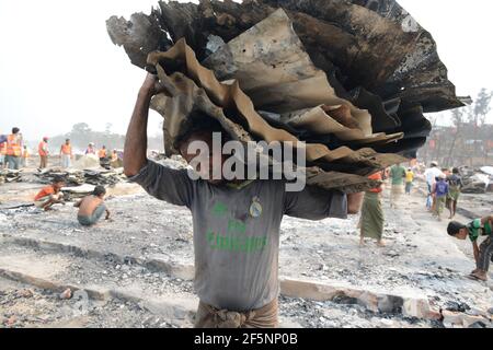 Un homme porte des restes charrés de ses effets à un Site d'abris temporaires mis en place pour les réfugiés déplacés de Rohingya jours après un incendie à un réfugié Banque D'Images