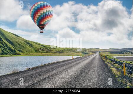 Montgolfière au-dessus des collines verdoyantes et de la route en Islande Banque D'Images