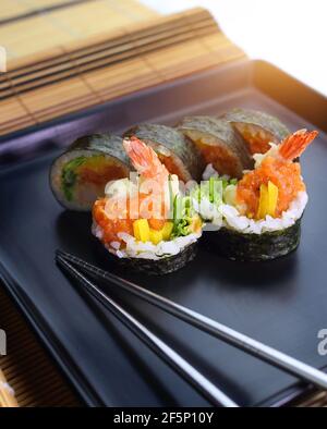 des petits pains à sushis savoureux et colorés servis sur une assiette noire Banque D'Images