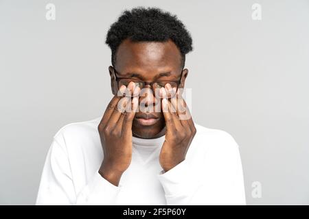 Épuisé Noir homme porter des lunettes frottant ses yeux se sent fatigué après le travail sur ordinateur portable. Fatigue Banque D'Images