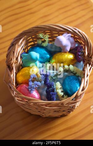 Panier avec œufs de pâques, lapins et fleurs sur une table en bois. Banque D'Images