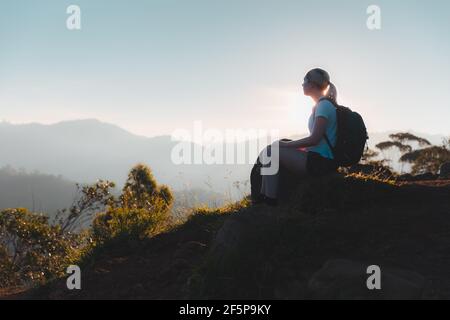 Silhouette d'une jeune femme routard appréciant un paisible et vue imprenable sur le coucher du soleil ou le lever du soleil après une randonnée en plein air au sommet Le petit pic d'Adam dans le Banque D'Images