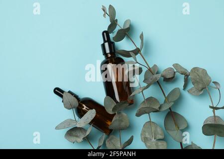 Flacons compte-gouttes d'huile et de brindilles d'eucalyptus sur fond bleu Banque D'Images