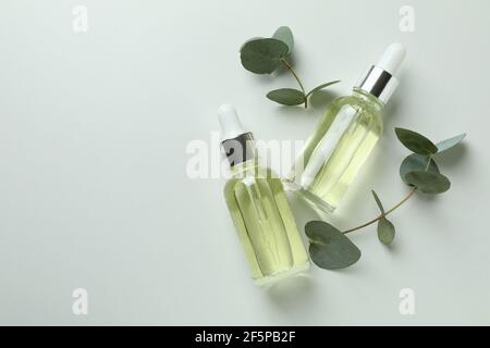 Flacons compte-gouttes d'huile d'eucalyptus et de brindilles sur fond blanc Banque D'Images