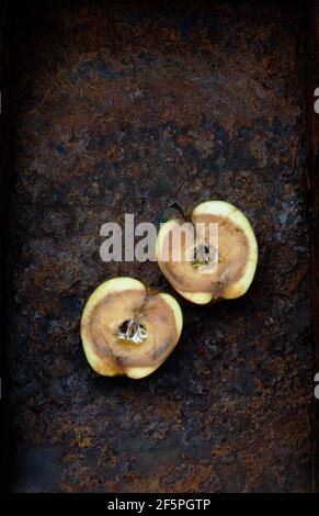 2 moitiés de pomme pourrie sur métal rouillé Banque D'Images