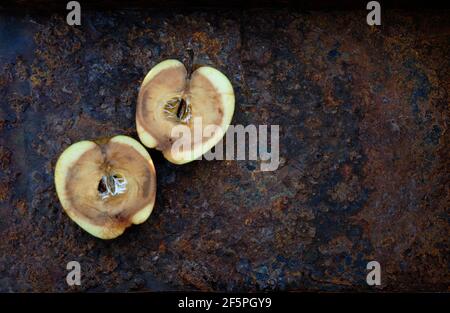 2 moitiés de pomme pourrie sur métal rouillé Banque D'Images