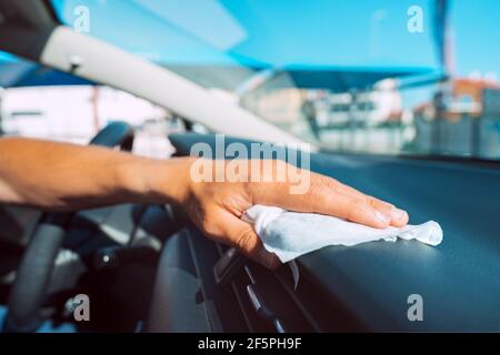 Gros plan de la main d'homme avec un essuie-tout antibactérien ou une serviette de nettoyage de panneau de voiture. Homme désinfectant salon de voiture de bactéries et de virus Banque D'Images