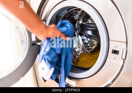 Adulte d'âge moyen asiatique homme chargement machine à laver avec souillé vêtements Banque D'Images