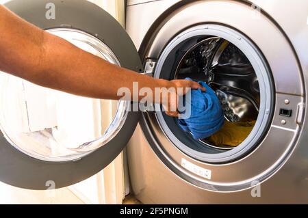 Adulte d'âge moyen asiatique homme chargement machine à laver avec souillé vêtements Banque D'Images