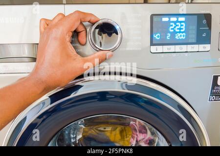 Adulte asiatique d'âge moyen, réglage du bouton rond de Machine à laver fabriquée par Samsung Banque D'Images
