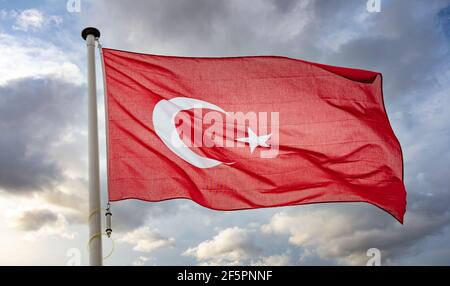 Symbole de la Turquie. Drapeau national turc sur un poteau agitant sur fond ciel nuageux. Banque D'Images