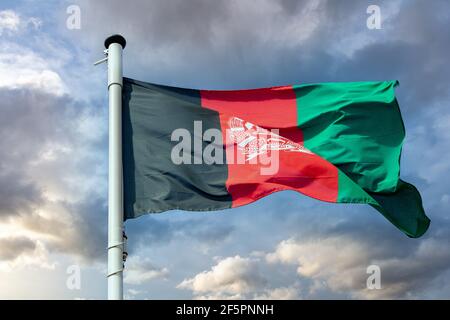 Symbole de l'Afghanistan. Drapeau national afghan sur un poteau agitant sur fond ciel nuageux. Banque D'Images