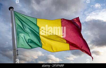 Symbole du Mali. Drapeau national du Mali sur un poteau agitant sur fond ciel nuageux. Banque D'Images