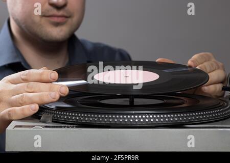 Un homme et un joueur de disque vintage pendant l'enregistrement, le disque tourne et la musique joue. Gramophone et l'idée de l'antiquité. Banque D'Images