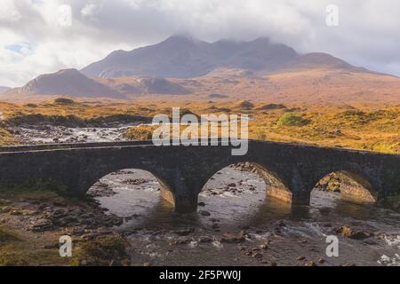 Vieux pont en pierre sur la rivière Sligachan avec le paysage de montagne des Cuillins noirs sur l'île de Skye dans les Highlands écossais, en Écosse. Banque D'Images