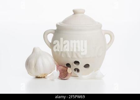 Une ampoule et une gousse d'ail frais avec un pot de conservation en céramique de conservation d'ail isolé sur un fond et une surface blanc plan. Banque D'Images