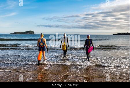 Des nageurs de femmes sauvages ou en eau libre portant des combinaisons avec des flotteurs de flottabilité entrent dans le Firth of Forth Sea, North Berwick, East Lothian, Écosse, Royaume-Uni Banque D'Images